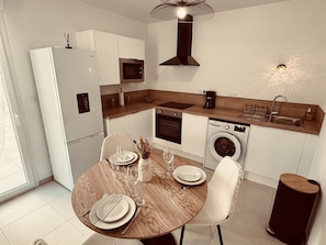 Eine moderne Küche mit Essbereich, ausgestattet mit Kühlschrank, Mikrowelle, Backofen und Waschmaschine.