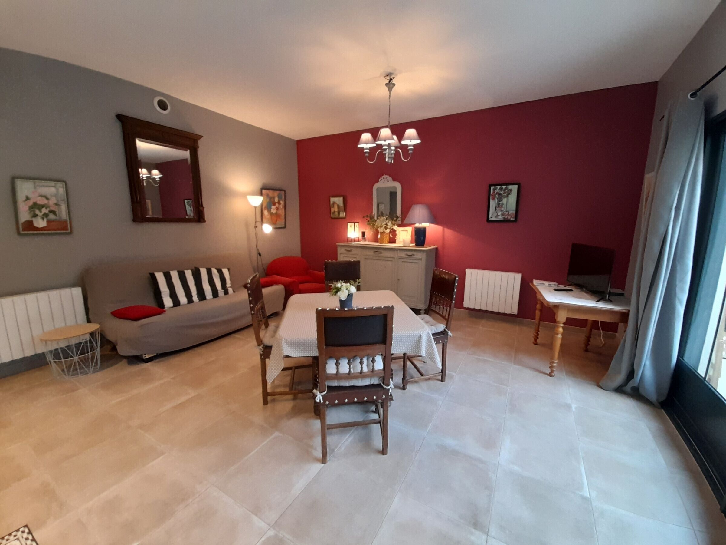 A living room with a dining table, chairs, a sofa, a TV, and a radiator.