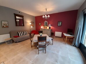 Een woonkamer met een eettafel, stoelen, een bank, een televisie en een radiator.