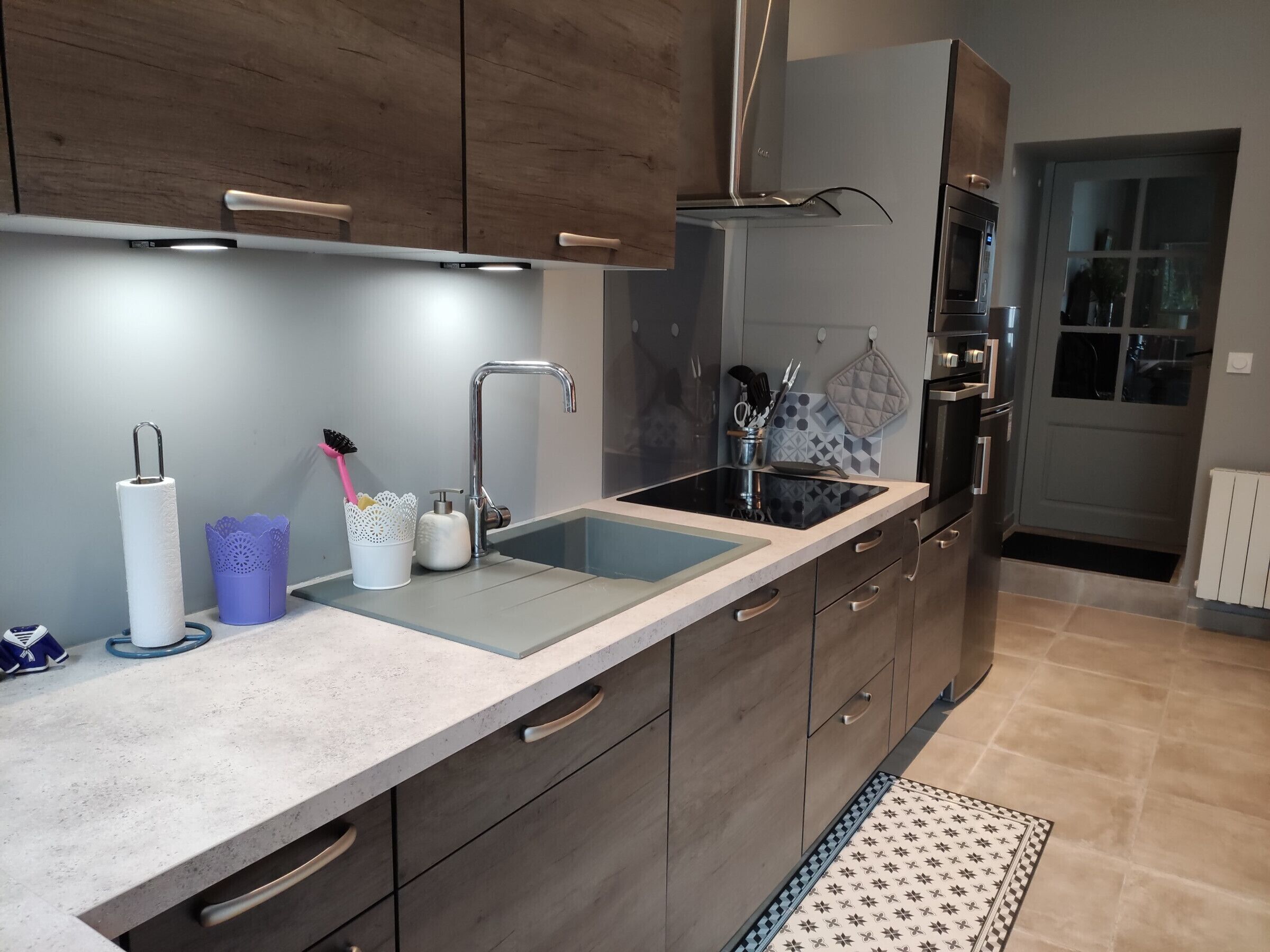 A modern kitchen with a double sink, stainless steel appliances, and wooden cabinets.