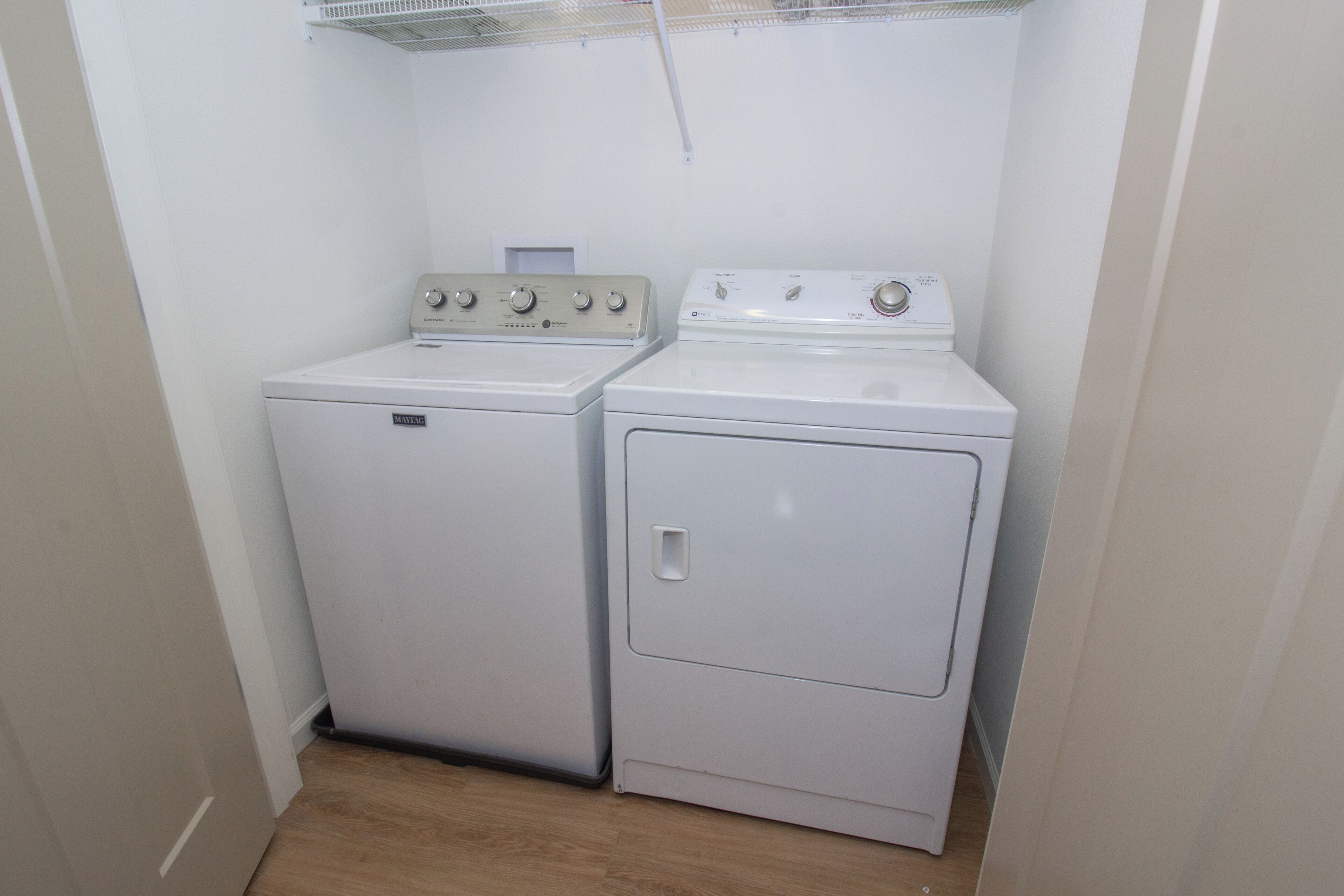 Une buanderie équipée d’un lave-linge à chargement frontal et d’un sèche-linge à chargement par le haut.