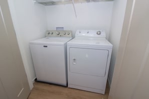 A laundry room with a front-loading washer and a top-loading dryer.