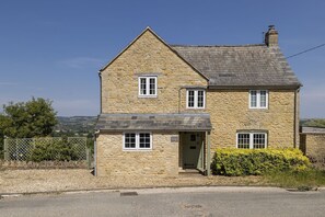 A two-story stone house with a gabled roof, a front door, and a small porch. - Murray's Cottage -  a cottage that sleeps 5 guests  in 3 bedrooms (Clapton-on-the-Hill)