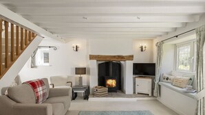 A cozy living room with a fireplace, a sofa, a television, and a staircase. - Murray's Cottage -  a cottage that sleeps 5 guests  in 3 bedrooms (Clapton-on-the-Hill)