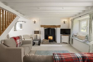 A cozy living room with a fireplace, a sofa, a television, and a staircase. - Murray's Cottage -  a cottage that sleeps 5 guests  in 3 bedrooms (Clapton-on-the-Hill)
