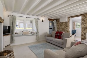 Ein gemütliches Wohnzimmer mit einer Couch, einem Fernseher und einer Steinwand.