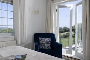 A bedroom with a bed, a chair, a view of the outdoors through a sliding door, and a window. - Murray's Cottage -  a cottage that sleeps 5 guests  in 3 bedrooms (Clapton-on-the-Hill)