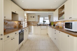 A kitchen with white cabinets, a wooden countertop, and a built-in microwave. - Murray's Cottage -  a cottage that sleeps 5 guests  in 3 bedrooms (Clapton-on-the-Hill)