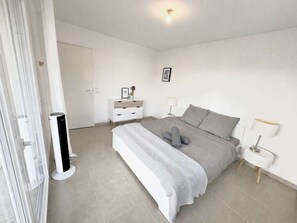 A modern bedroom with a bed, bedside tables, a wardrobe, and a radiator. - Apartment with pool and parking - 4 guests (Le Lavandou)