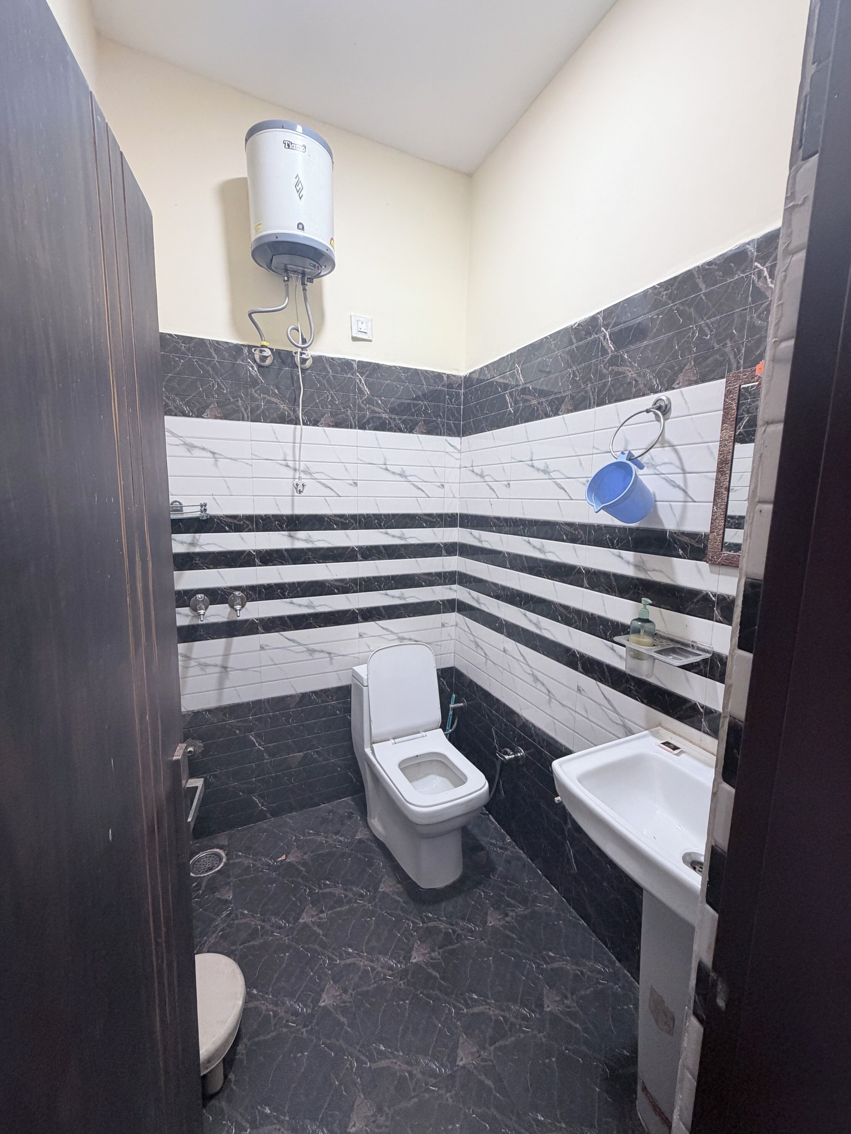 A bathroom with a toilet, a sink, and a water heater mounted on the wall.