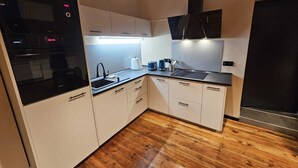 Cocina moderna con armarios blancos, horno negro y extractor de acero inoxidable.