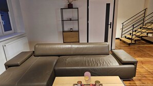 Una sala de estar moderna con un sofá modular, una mesita de madera con velas y una escalera.