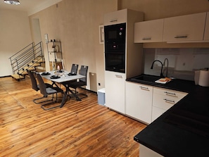 A compact kitchen with a dining area, wooden flooring, and a staircase. - Old School: Open living/kitchen area, bedroom, modern bathroom (Lasów)