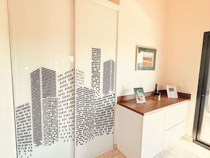 Ein Empfangsschalter mit Stadtbildkunstwerk an der Wand, einem gerahmten Willkommensschild und einer Flasche auf der Theke.