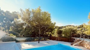 Uma piscina retangular com superfície de água azul translúcida, rodeada por um deck revestido com azulejos.