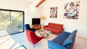 Uma sala de estar moderna com um sofá vermelho, uma poltrona azul e uma televisão.
