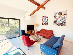 Ein modernes Wohnzimmer mit einem roten Sofa, einem blauen Sessel und einem Fernseher.