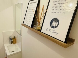 A framed menu with text and a candle holder on a wooden shelf in a bathroom. - Apartment with AC, parking, near the sea (Le Lavandou)