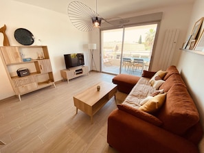 Ein modernes Wohnzimmer mit einer Couch, einem Couchtisch, einem Fernseher und einem Essbereich mit Stühlen.