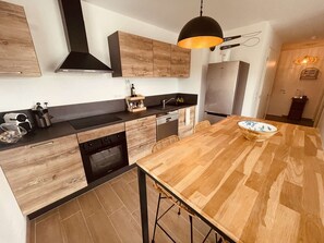 Eine moderne Küche mit Holzschränken, einer Mittelinsel und einem eingebauten Backofen.
