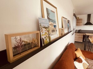 A living room with a sofa, a coffee table, and framed artwork on the wall. - Apartment with AC, parking, near the sea (Le Lavandou)
