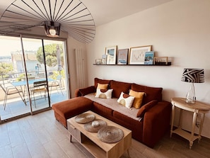 A living room with a brown sofa, a wooden coffee table, and a ceiling fan. - Apartment with AC, parking, near the sea (Le Lavandou)