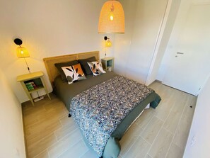 A bedroom with a bed, two bedside tables, a lamp, and a door. - Apartment with AC, parking, near the sea (Le Lavandou)