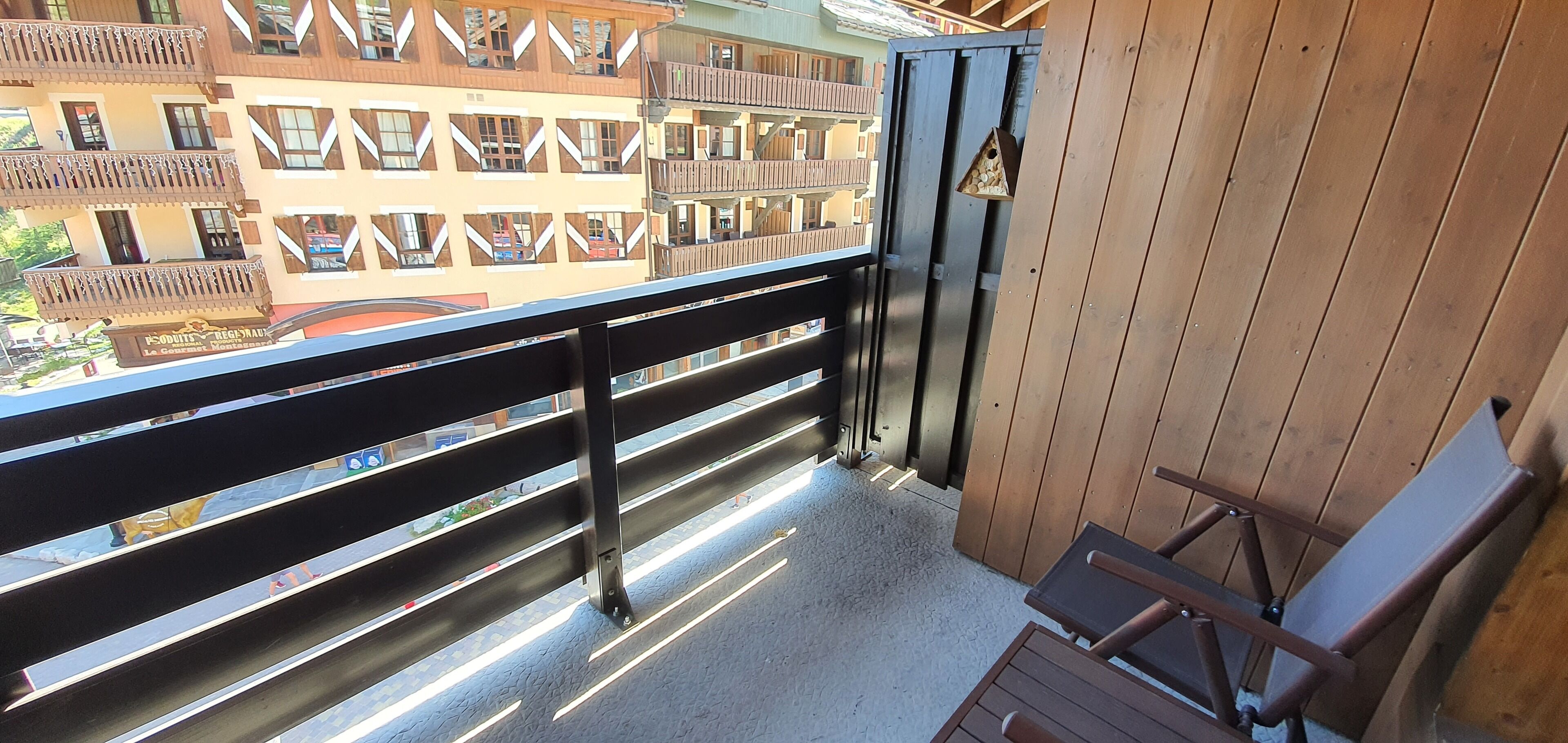 Un balcon avec une balustrade en bois, une chaise et une nichoir.