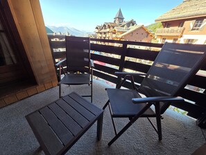 A balcony with two chairs and a small table, overlooking a mountainous landscape with traditional buildings. - Auberge Jérôme 614 — 80 m² duplex, 3 bedrooms, ski-in/ski-out, 5★ with a pool (Bourg-Saint-Maurice)