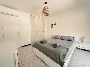A bedroom with a bed, a wardrobe, a bedside table, and a hanging light fixture. - Renovated apartment with parking - 6 guests (tennis view) (Bormes-les-Mimosas)