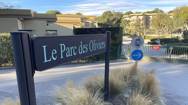 En skylt för ”Le Parc des Oliviers” med en pil som visar riktningen.