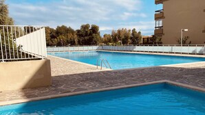 En swimmingpool med en stenbelagd poolkant och ett staket av metall.