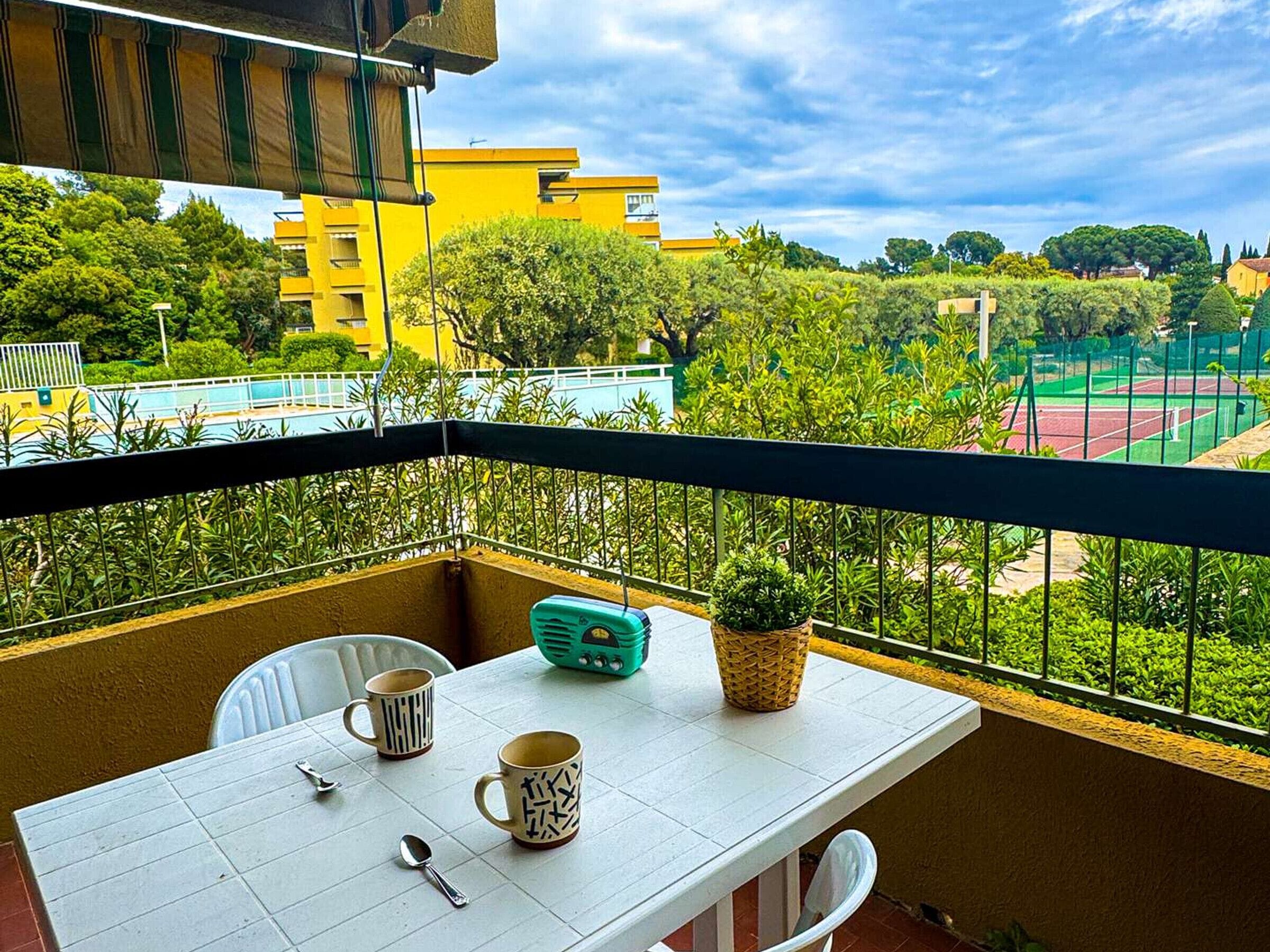 A balcony with a table, two mugs, a spoon, and a radio.