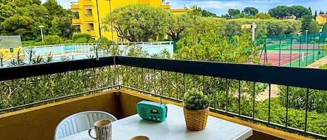A balcony with a table, two mugs, a spoon, and a radio.