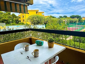 Ein Balkon mit Tisch, zwei Tassen, einem Löffel und einem Radio.