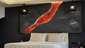 A bedroom with a bed, a large abstract painting, and two wall-mounted lights. - Bevimar Lava Suite with Private Pool and Non Heated Jacuzzi (Finikia)