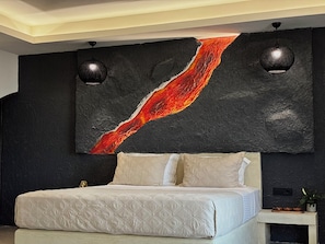 A bedroom with a bed, a large abstract painting, and two wall-mounted lights. - Bevimar Lava Suite with Private Pool and Non Heated Jacuzzi (Finikia)