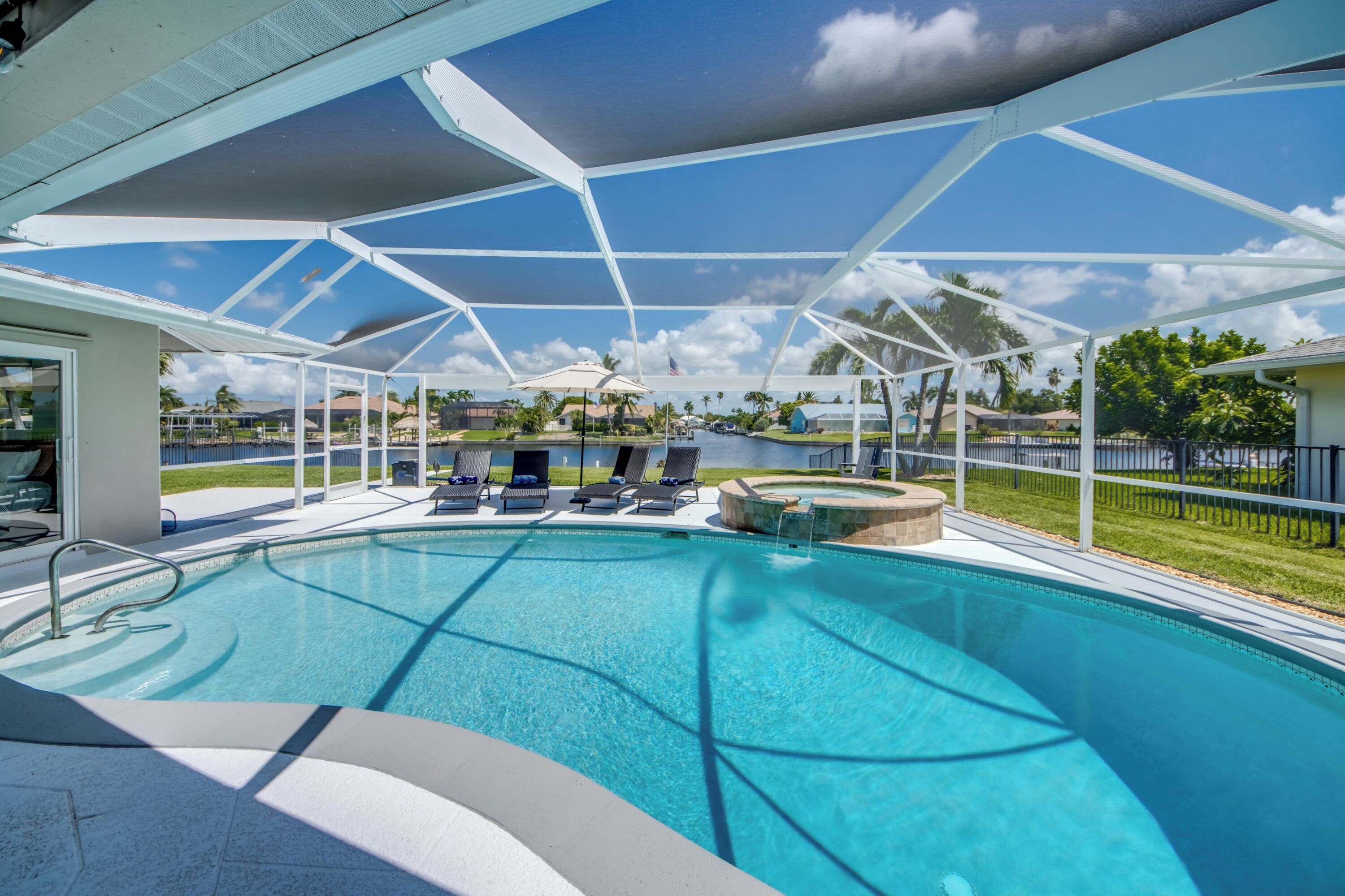 A swimming pool with lounge chairs and a covered area.