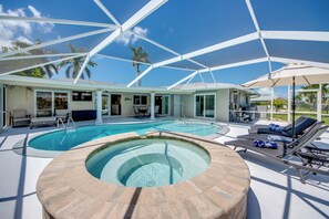 Ein Poolbereich mit Whirlpool, Liegestühlen und Sonnenschirmen.