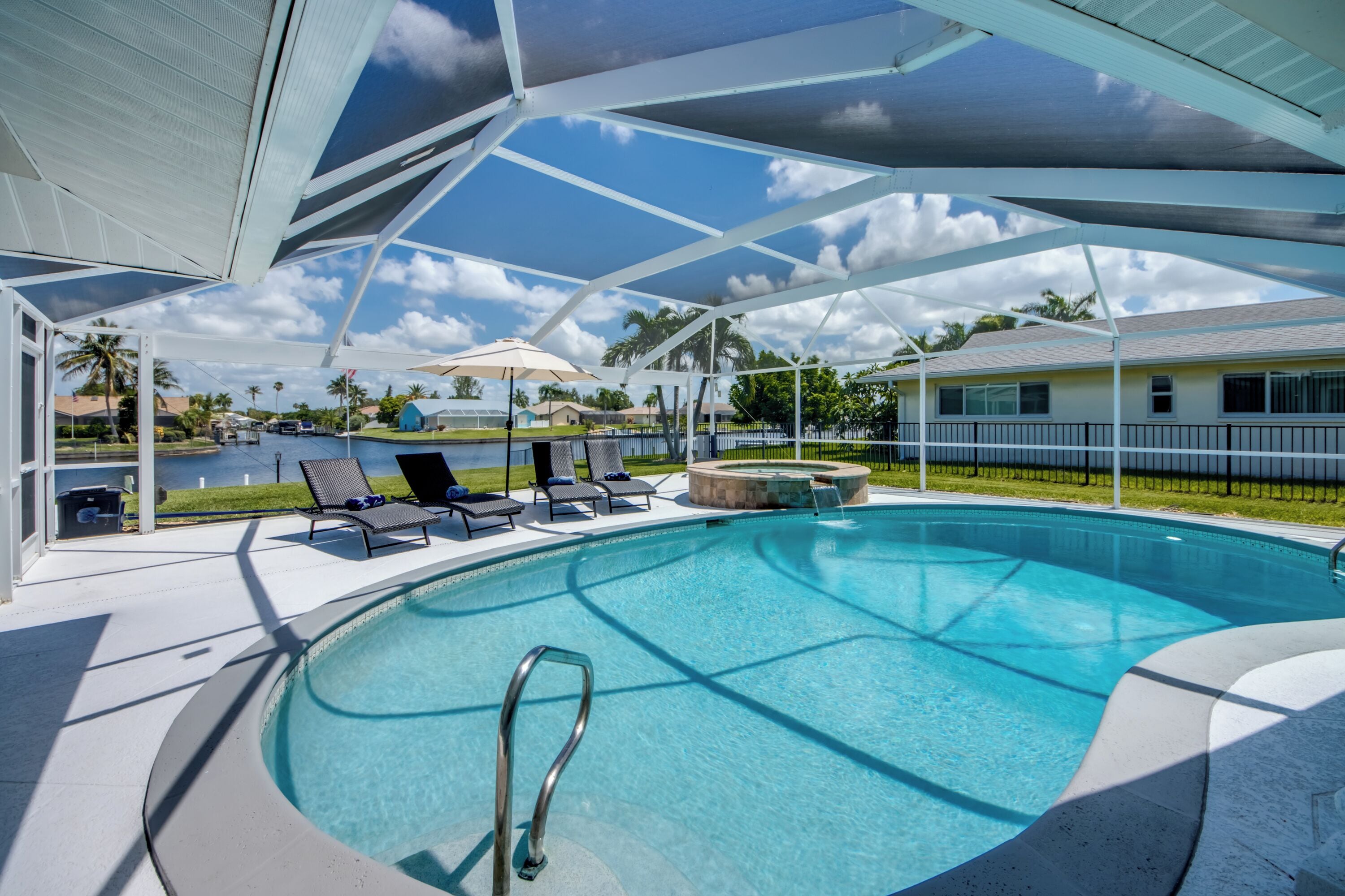 A swimming pool with a covered area, lounge chairs, and a view of the surrounding landscape.