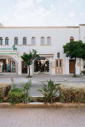 Ein Gebäude mit einer Fassade, auf der 'APMAKEIO' steht, und ein Baum im Vordergrund.