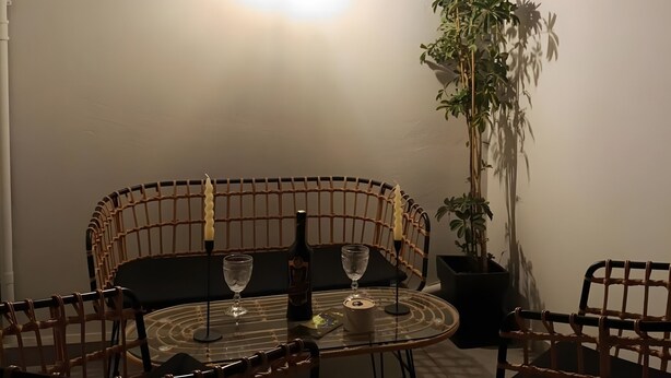 A room with a round glass table, two chairs, a potted plant, and a ceiling light fixture. - Casa Autentica 1933 Apartment with Private Balcony (Kos)