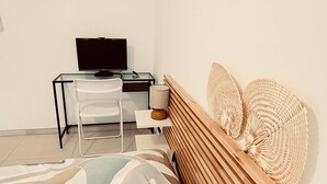 Un dormitorio con cama, escritorio con computadora y una silla.