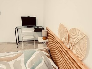 Ein Schlafzimmer mit einem Bett, einem Schreibtisch mit Computer und einem Stuhl.