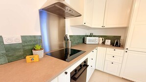 Una cocina moderna con estufa integrada, microondas y hervidor. Hay un letrero de bienvenida y una planta en maceta sobre la encimera.