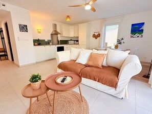 Ein modernes Wohnzimmer mit einem weißen Sofa, einem kleinen runden Tisch und einem Deckenventilator.