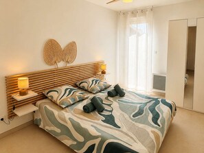 Een slaapkamer met een bed, nachtlampjes, een decoratief object aan de muur en een raam met gordijnen.
