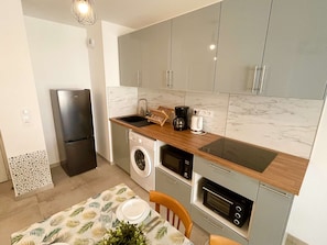 A compact kitchen with a built-in washing machine, a coffee maker, and a microwave. - Apartment, air conditioning, parking - 4 guests (Le Lavandou)