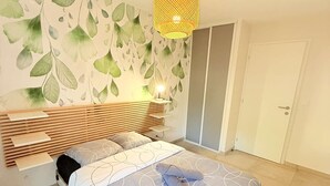 Ein Schlafzimmer mit Bett, Nachttisch, Wandlampe und Kleiderschrank.