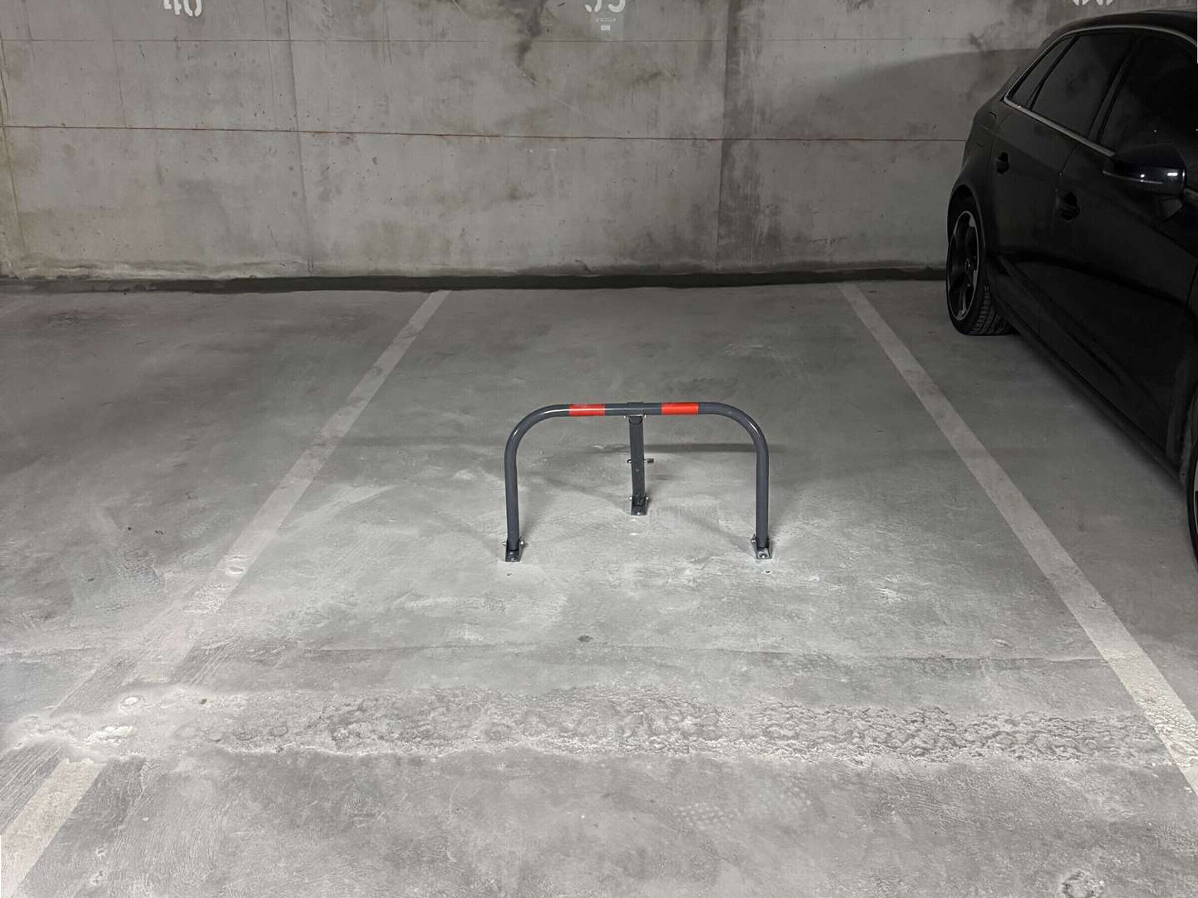 A parking garage with a concrete floor and a metal barrier.